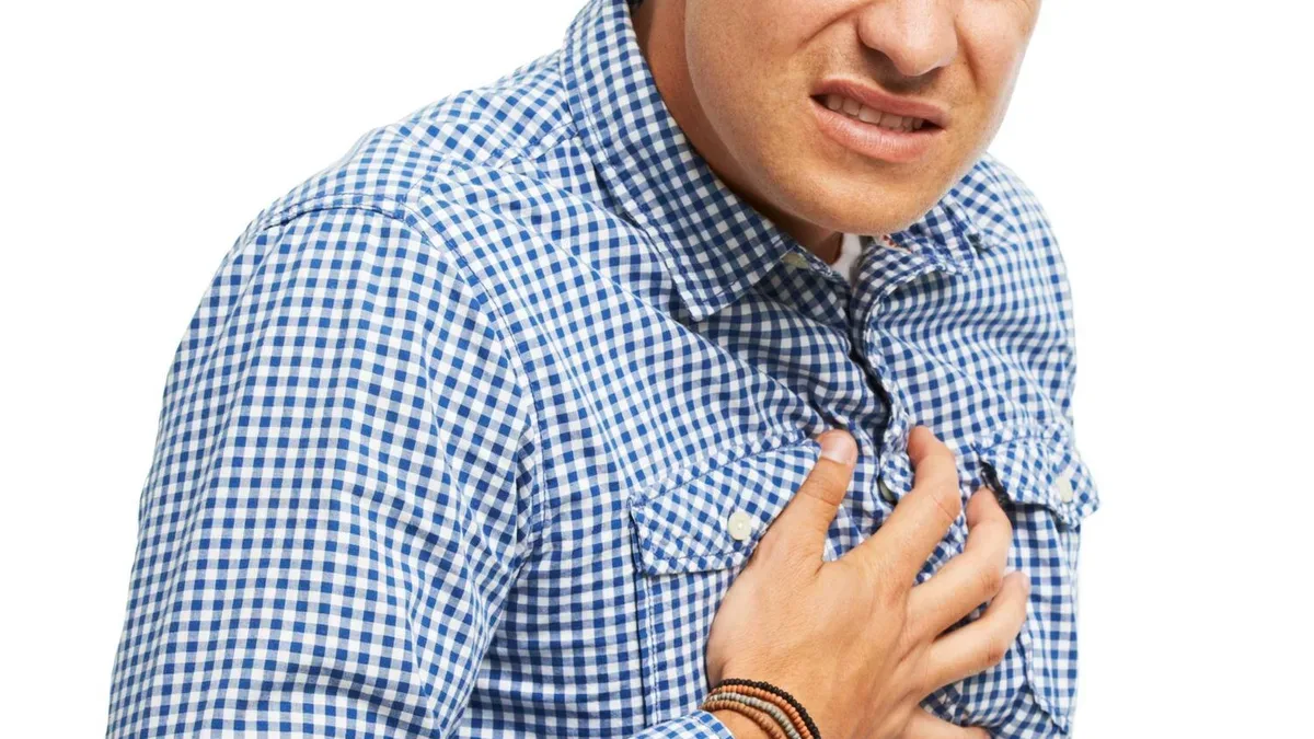 Hombre agarrándose el pecho por dolor precordial, síntoma de alarma de emergencia cardiovascular