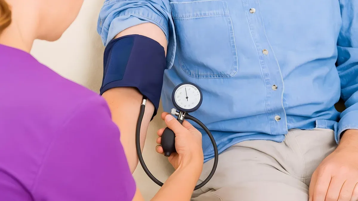 Enfermera mide la presión arterial de un paciente con tensiómetro en una clínica para controlar la hipertensión